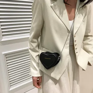 Détail d'un mini sac à bandoulière noir en forme de cœur avec chaîne argentée