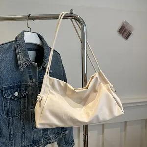 Detail of soft cream tote bag with side drawstring and embossed lettering on faux leather