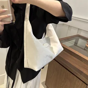 Detail einer weißen Hobo-Tasche mit matter Wildleder-Optik und Markenlogo am Model