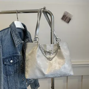 Close-up of metallic silver tote bag with double chain and bow charm on a hanger