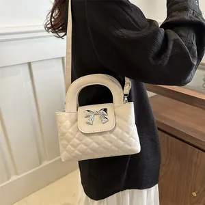 Detail of white quilted handbag featuring a silver metal bow buckle and reinforced handle