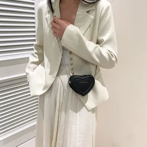 Détail du petit sac à bandoulière noir en forme de cœur avec chaîne en métal argenté