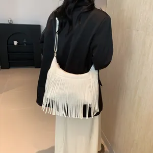 Sac à bandoulière blanc à franges porté par un mannequin en blazer noir moderne
