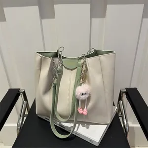 Detail of cream and green tote bag with Fashion logo and plush charm on a chair