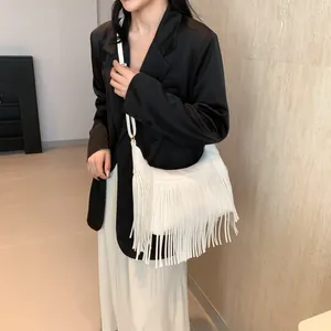 Détails du sac à bandoulière blanc à franges porté avec blazer noir et jupe blanche