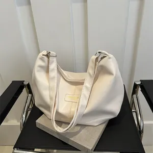 Detail of soft cream PU leather shoulder bag with decorative fashion label on a chair