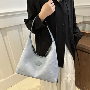 Detail der hellblauen Hobo-Tasche mit Wildlederoptik und ovalem Fashion-Etikett