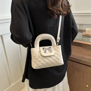 Close-up of white quilted handbag with silver bow detail and sleek top handle strap