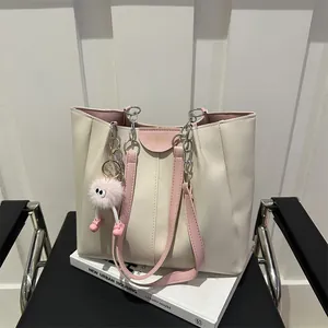 Close-up of cream tote bag with pink straps, metallic chain, and plush charm detail