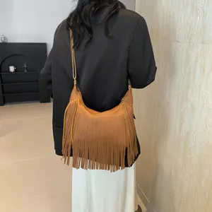Sac hobo en cuir marron à franges porté à l'épaule dans un décor intérieur chic