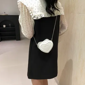 Détail du mini sac bandoulière blanc en cuir en forme de cœur avec chaîne argentée