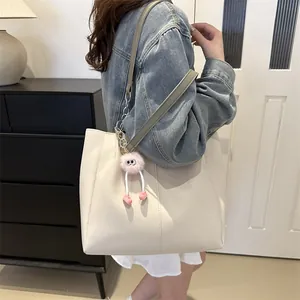 Large cream tote bag with stylish shoulder strap and pink plush doll charm decoration