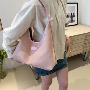 Detailansicht der rosa Hobo-Tasche aus strukturiertem Stoff mit Schultergurt am Modell