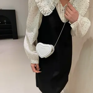 Vue détaillée du mini sac bandoulière blanc en forme de cœur avec chaîne sur modèle
