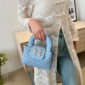 Close-up of light blue quilted leather bag with silver bow hardware and handle