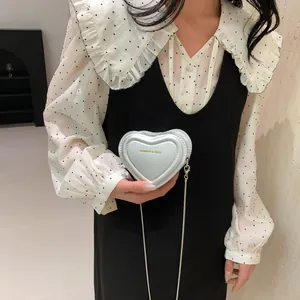 Mini sac bandoulière chic en forme de cœur avec lettrage doré sur un mannequin