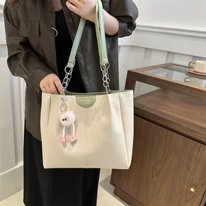 Chic beige tote bag with green chain handles and pink plush charm for spring fashion