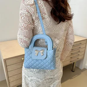 Close-up of quilted light blue handbag with silver bow detail worn by a model