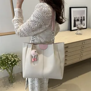 Large beige tote bag with pink trim, metal chain strap and cute monster plush charm