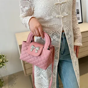 Pink quilted handbag with silver bow detail shown worn by a model in a casual setting