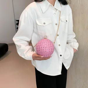 Detail der rosa kugelförmigen Abendtasche mit Strass und Goldkette an einem Model