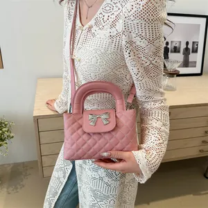 Close-up of pink quilted crossbody bag with silver bow hardware and handle