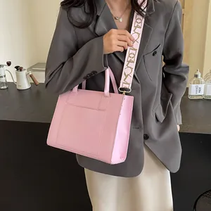Sac fourre-tout rose en cuir avec large bandoulière en tissu à motifs sur un mannequin