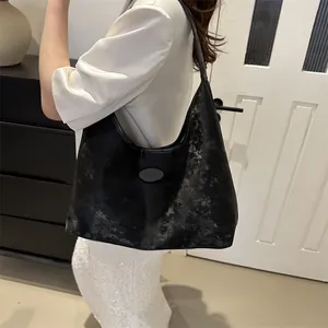 Detailansicht der schwarzen Hobo-Bag mit Vintage-Textur, ovalem Logo und mattem Finish