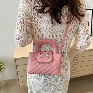 Detailed view of pink quilted handbag with silver bow charm on a white crochet dress