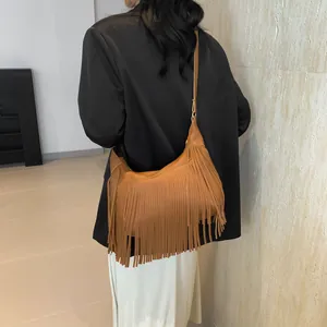 Sac hobo en cuir marron à franges style bohème porté par un mannequin dans une pièce