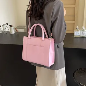 Détail du sac cabas rose avec large bandoulière texturée dans un cadre de café moderne
