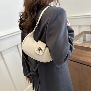 Detail of the cream crescent hobo bag with a gold clover clasp shown on a model