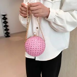 Rosa kugelförmige Abendtasche mit Strass und Goldkette, gehalten von einem Modell