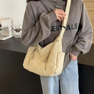 Detail van gebroken witte canvas crossbodytas met dubbele ritsen en verstelbare riem