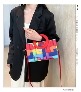 Detail of vibrant geometric patchwork handbag with iconic red circular handle
