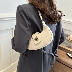 Creamy crescent hobo bag with vintage gold floral clasp shown on model's shoulder
