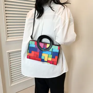 Detail showing colorful geometric patterned crossbody bag worn by a model in a white shirt