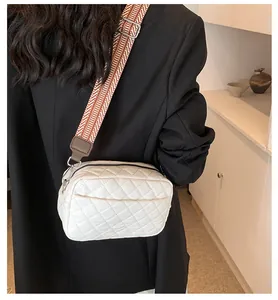 Detail of white quilted nylon crossbody bag featuring a woven strap and double zippers
