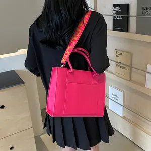 Détail du cabas rose vif avec large bandoulière en jacquard et poche plaquée devant