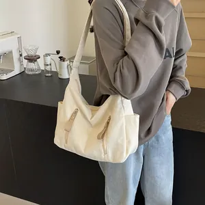 Detail van de crème canvas hobo tas met dubbele verticale ritsen en zijvakken op de tas
