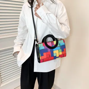 Fashionable colorful checkered square bag with a round handle styled on a model's shoulder