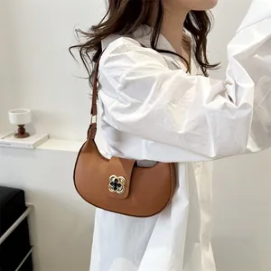 Detail of brown crescent bag with a golden floral buckle and smooth leather texture