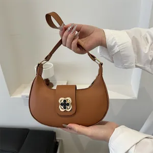 Detailed macro of vintage brown crescent bag with a gold clover clasp and top zipper