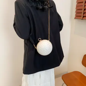 Elegante gewebte Kugeltasche in Cremeweiß, getragen von einem Modell in Abendkleidung
