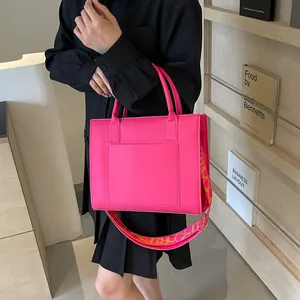 Sac fourre-tout en cuir rose vif avec une large bandoulière à motifs et style épuré