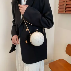 Detaillierte Nahaufnahme einer perlweißen Kugel-Clutch mit goldener Kette
