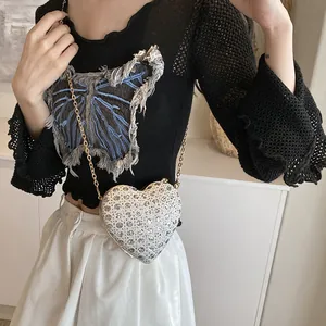 Vue détaillée du sac de soirée cœur en strass argentés avec chaîne dorée sur modèle