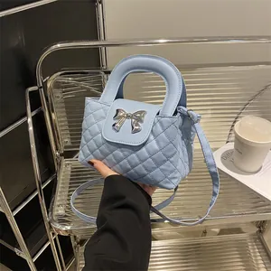 Detail of light blue quilted handbag with silver bow hardware in a lifestyle setting