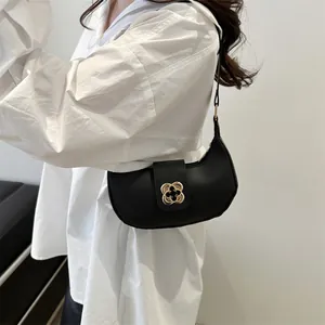 Detail of black crescent hobo bag featuring a decorative golden flower metal buckle