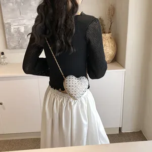 Détail du sac de soirée argenté en forme de cœur avec strass et fine chaîne dorée